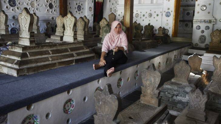 A woman sits among the tombstones at the shrine. Some conservative Muslims frown upon the burial of human beings in a house of worship and pilgrimages to such shrines. Photo: Irwin Fedriansyah