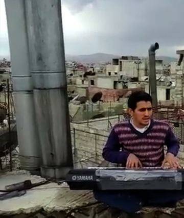 Ayham al-Ahmad rehearses a song on a rooftop in Yarmouk refugee camp. Photo: Supplied