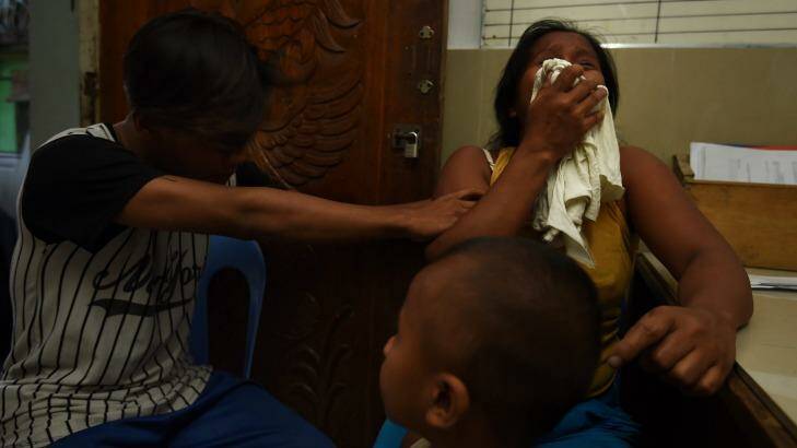 A neighbour comforts pregnant Ruth-Jane Sombrio, widow of Rogie Sebastian, who was killed by police in his home on  September 19.  Photo: Kate Geraghty