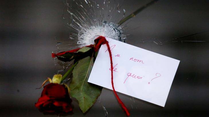 A rose in a bullet hole with a note that translates to "In the name of what?" at La Belle Equipe in Paris on Sunday. Photo: Andrew Meares