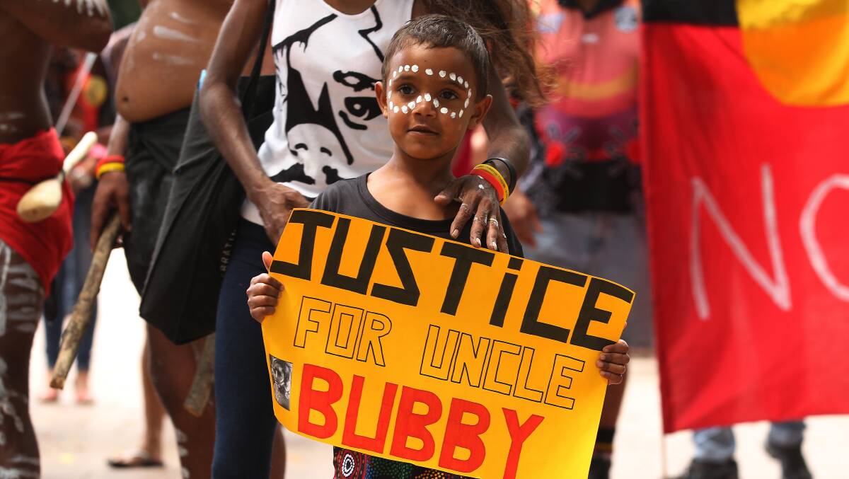 Justice Kirk, 5 holds a sign about his uncle Clinton Speedy-Duroux, who was killed aged 16 in 1991. Photo: KATE GERAGHTY