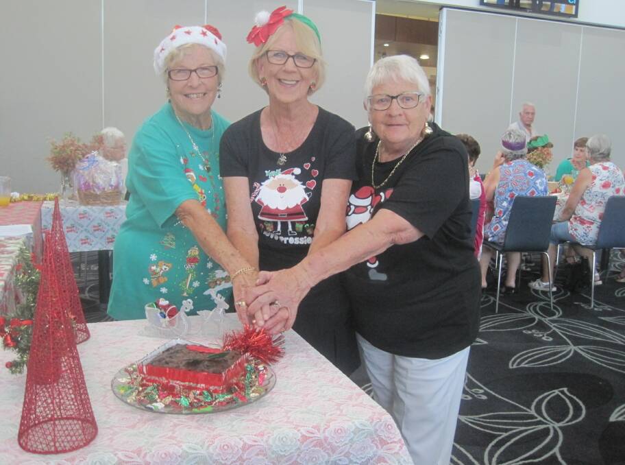 Sylvia Mitchell, Jo Bathgate and Helen Fisher cut the Christmas cake at Urunga women's bowls