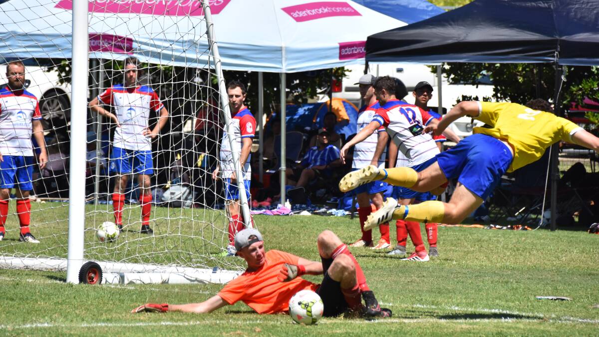 A West Pymble player goes flying after this challenge by Nambucca Strikers goalkeeper Corey Forbes. Photo: Christian Knight