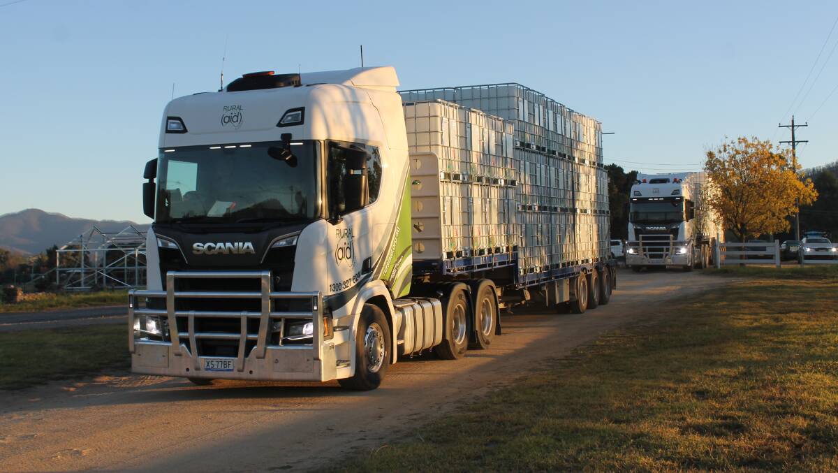 HERE TO HELP: The water tanks enter the Cobargo Showground on the backs of three Rural Aid trucks on Thursday morning. 