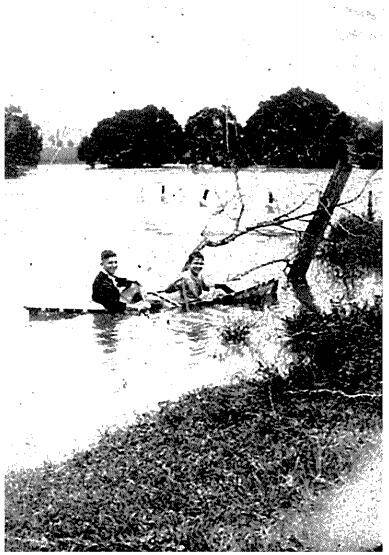 Merv Lynch and friend cross the flooded Nambucca River by canoe - the old wooden Lanes Bridge is barely visible beneath the rising water. Image supplied by Mr Lynch
