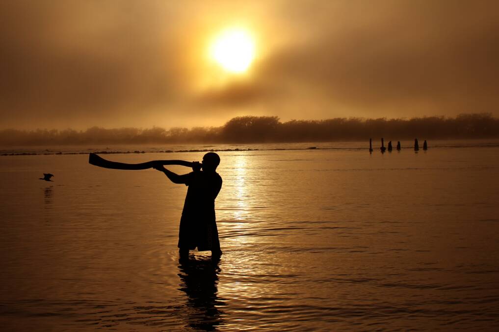 Robert Canning playing the didgeridoo as the sun rises in Urunga. Photo by Peter Lister