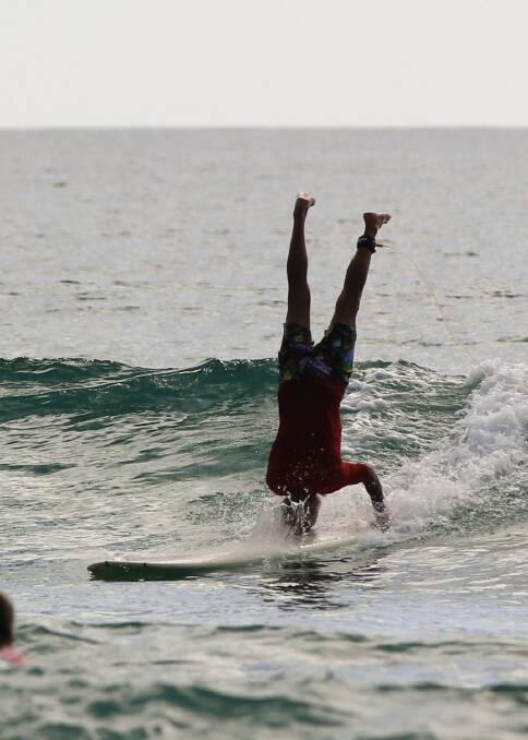 John Shorter pulls off a headstand in the surf off Scotts Head Beach. Photo: Mick Birtles.