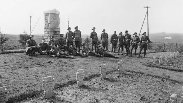 Unidentified Australian soldiers in front of a memorial in a cemetery where eighty-one French and German soldiers, who fell in battle on August 23, 1914, lie buried. Photo: courtesy Australian War Memorial
