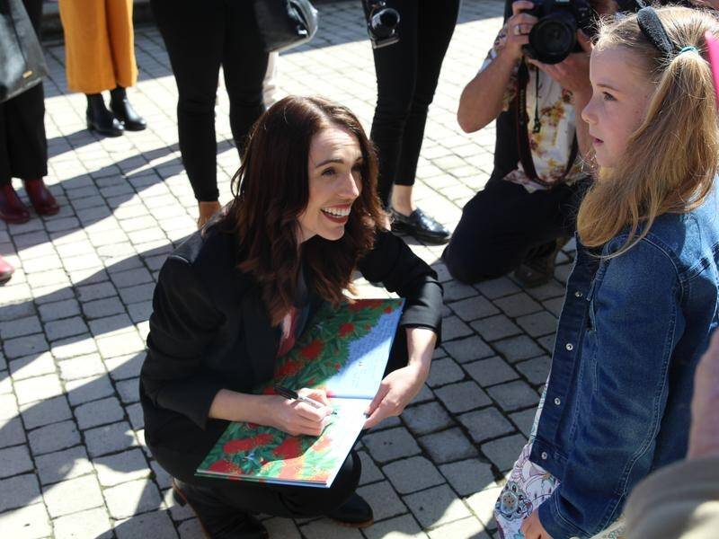 NZ PM Jacinda Ardern signs the book of young Bennett Bellinger-Judd while on the campaign trail.